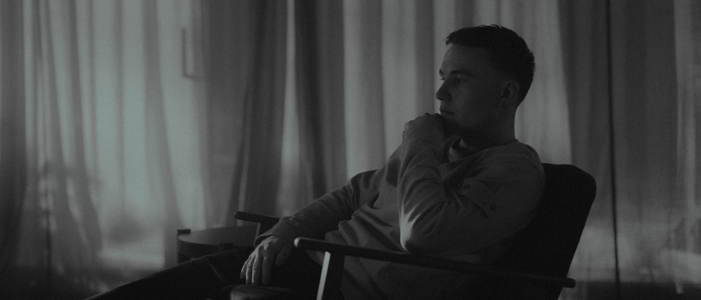 The same man in profile, hand at his chin, in black and white