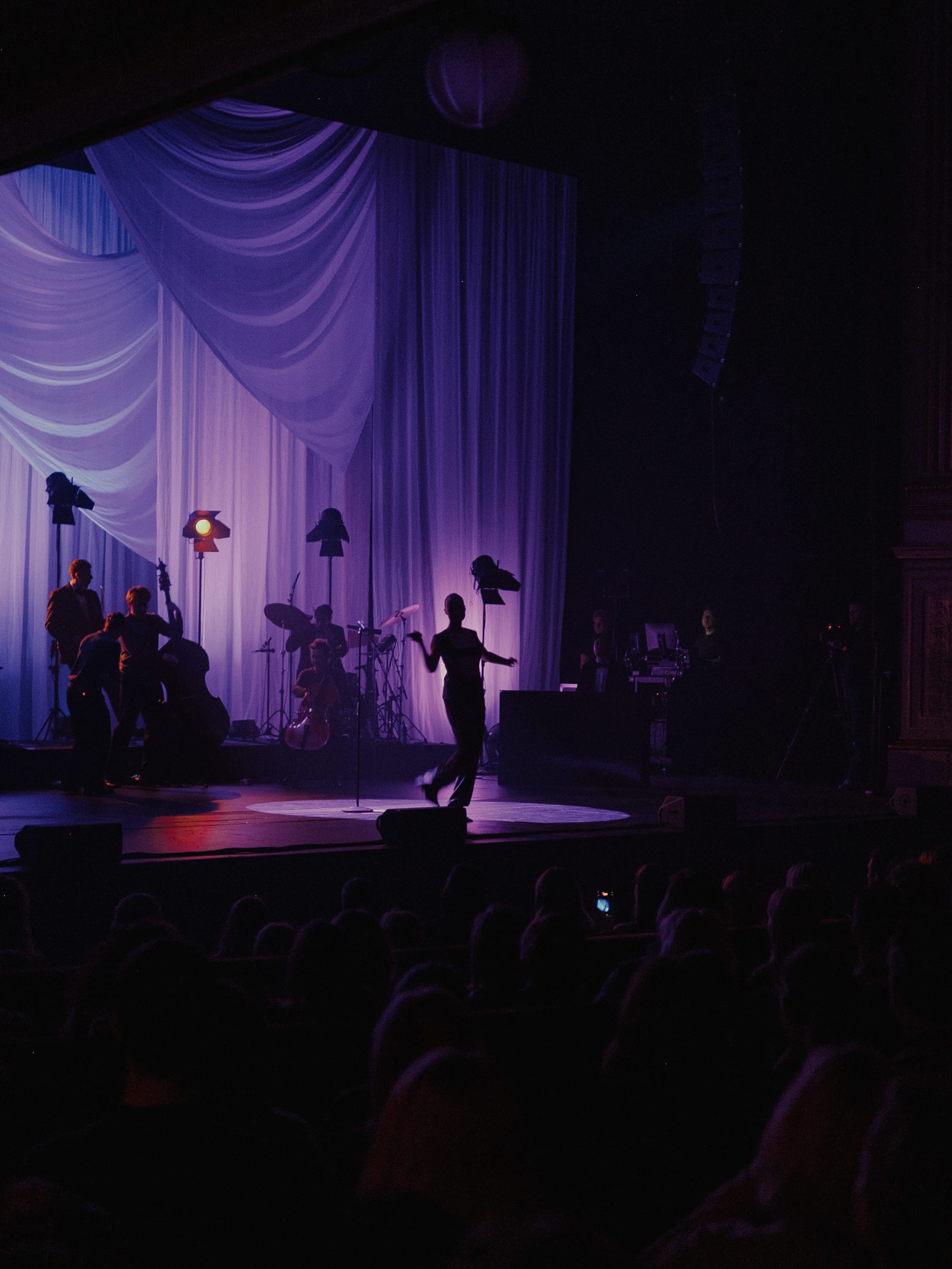 A band on a purple-lit stage, the singer mid-stride at the front