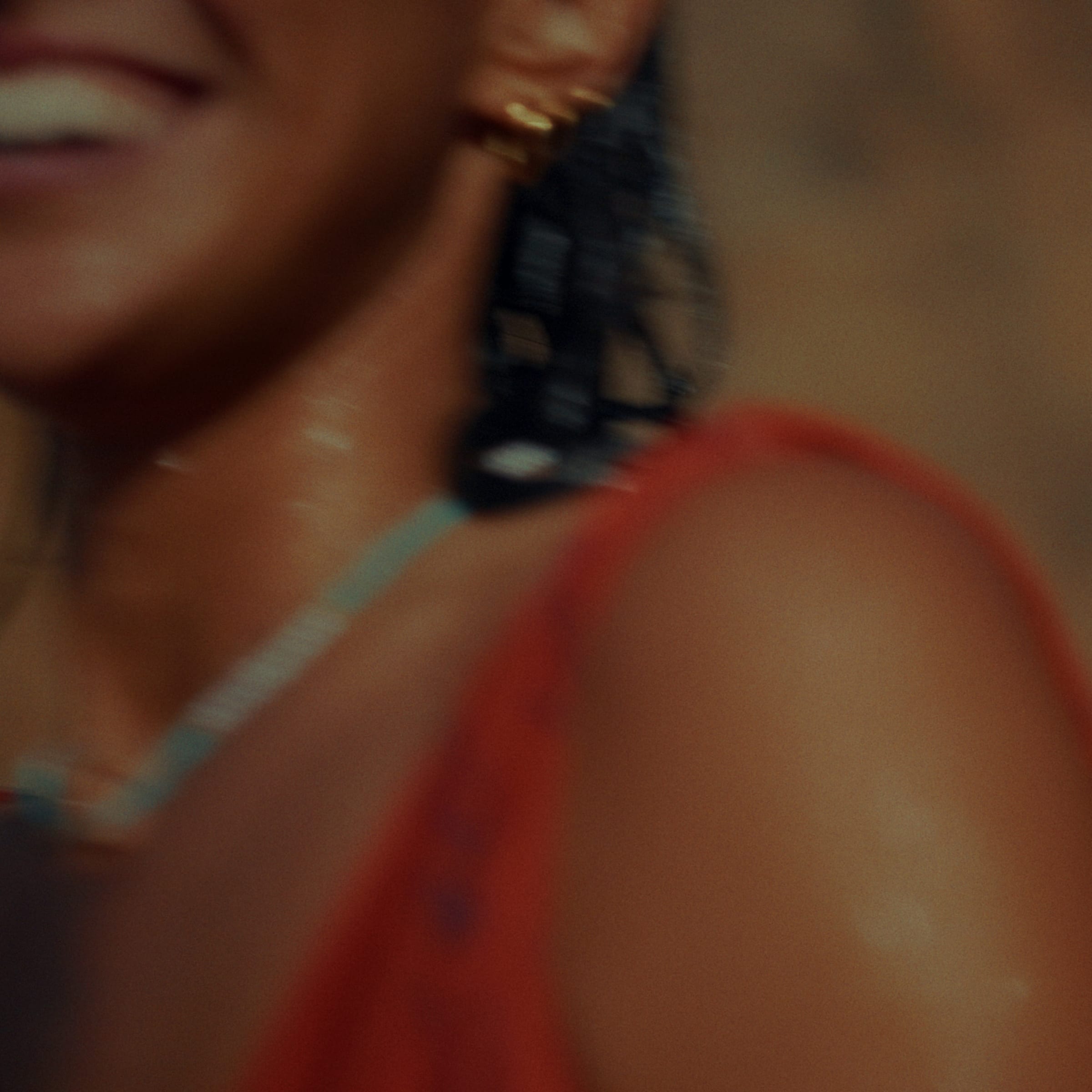 A smiling woman close to the lens and out of focus, gold earring, red top